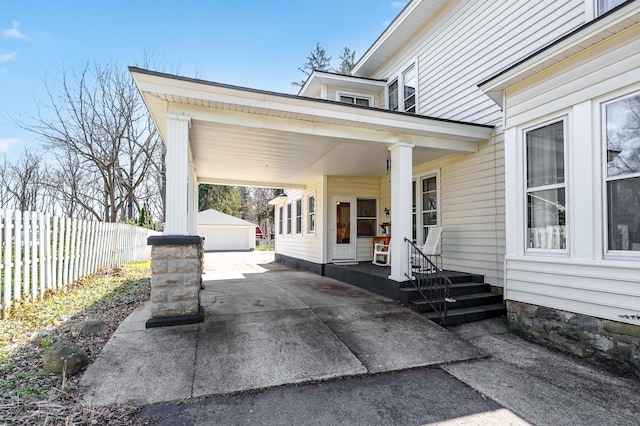 551 W Bridge St, Plainwell, MI 49080 - view of patio featuring concrete driveway, an outdoor structure, and fence