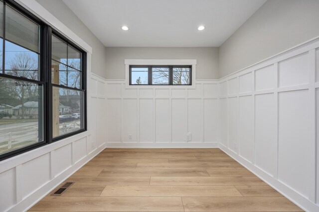 7701 Fase St SE Lot 15, Ada, MI 49301 - unfurnished room with a wainscoted wall, a decorative wall, light wood-style flooring, and visible vents
