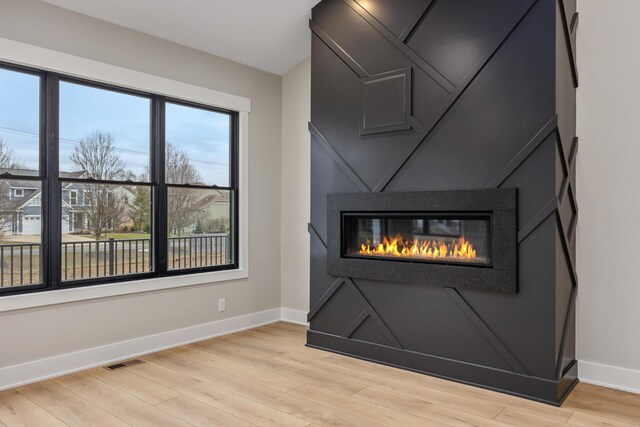 7701 Fase St SE Lot 15, Ada, MI 49301 - room details featuring a glass covered fireplace, baseboards, wood finished floors, and visible vents