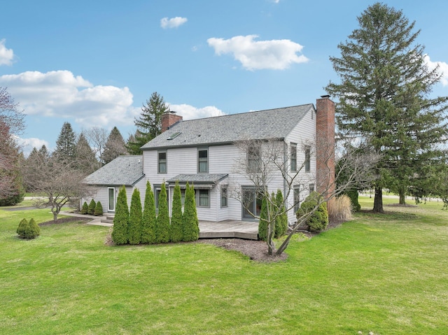 rear view of house featuring a chimney, a deck, and a yard