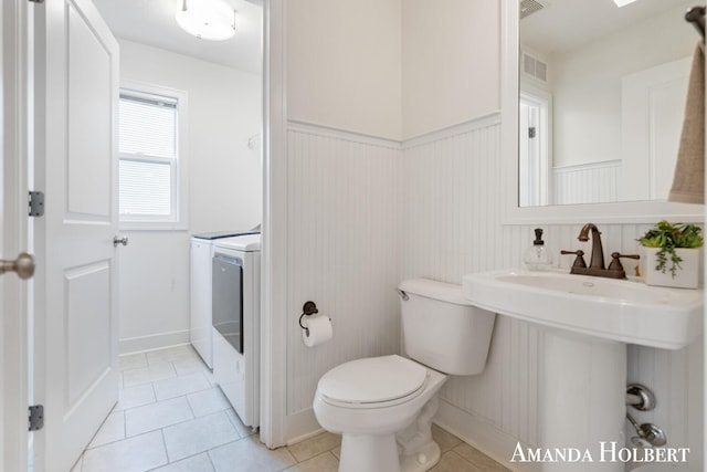 bathroom featuring visible vents, toilet, a wainscoted wall, washer and clothes dryer, and tile patterned flooring