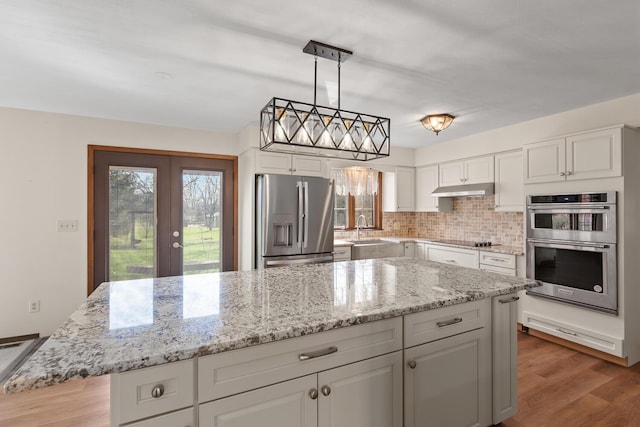 4675 Treat Hwy, Adrian, MI 49221 - kitchen featuring white cabinetry, appliances with stainless steel finishes, wood finished floors, under cabinet range hood, and decorative backsplash