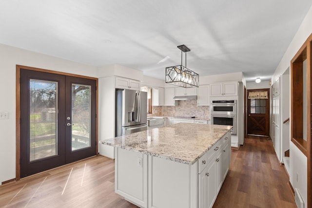 4675 Treat Hwy, Adrian, MI 49221 - kitchen with white cabinets, appliances with stainless steel finishes, light stone counters, french doors, and backsplash