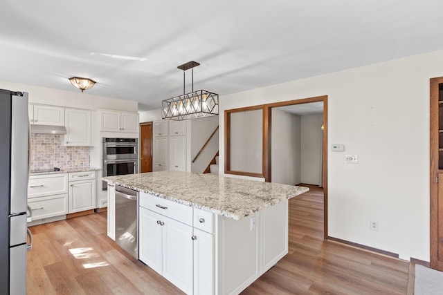 4675 Treat Hwy, Adrian, MI 49221 - kitchen featuring white cabinets, appliances with stainless steel finishes, under cabinet range hood, light wood-style flooring, and decorative backsplash