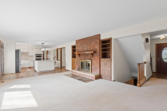 4675 Treat Hwy, Adrian, MI 49221 - unfurnished living room featuring a brick fireplace, a chandelier, and light carpet