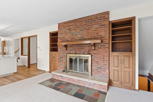 4675 Treat Hwy, Adrian, MI 49221 - living area featuring built in shelves, light colored carpet, a brick fireplace, and stairs