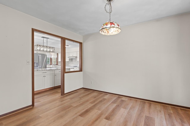 4675 Treat Hwy, Adrian, MI 49221 - empty room with light wood-style flooring, a chandelier, a sink, and baseboards