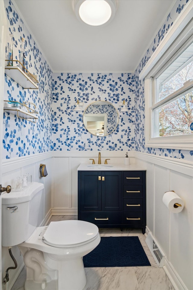 bathroom with visible vents, toilet, wainscoting, and wallpapered walls