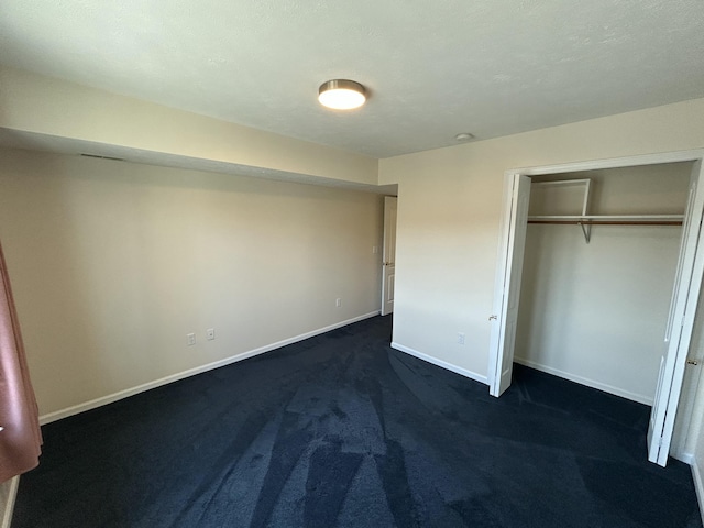 unfurnished bedroom featuring dark carpet, a closet, and baseboards