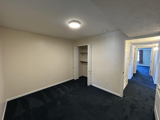 unfurnished bedroom featuring a closet, baseboards, and dark carpet