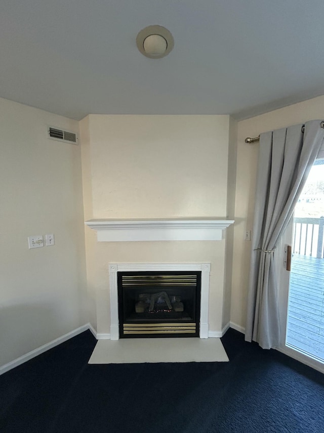 room details featuring a glass covered fireplace, visible vents, baseboards, and carpet floors