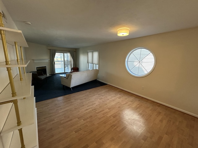 unfurnished living room with a fireplace, baseboards, and wood finished floors
