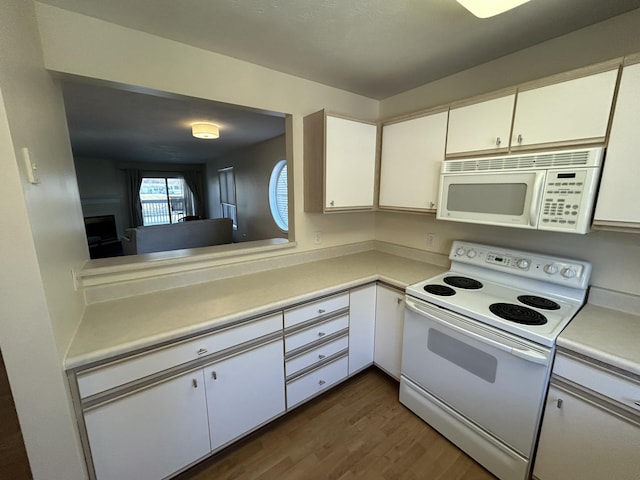 kitchen featuring white cabinetry, dark wood-style flooring, light countertops, and white appliances
