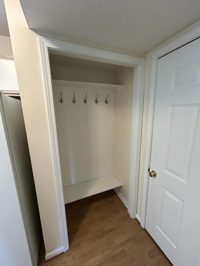 mudroom with light wood-style flooring, baseboards, and a textured ceiling
