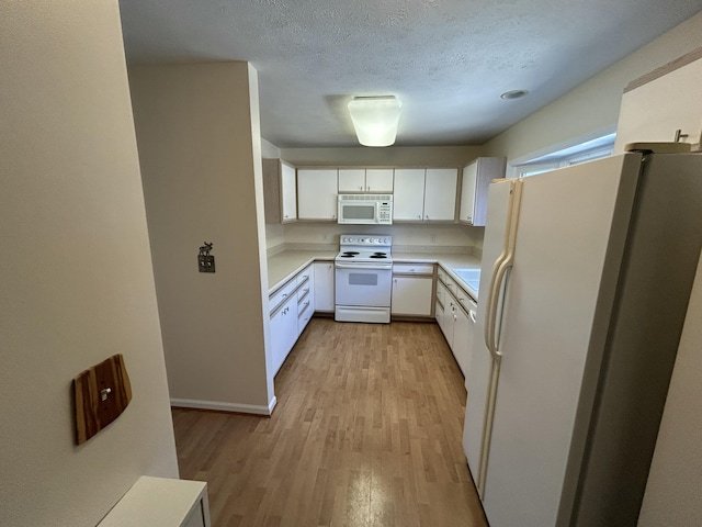 kitchen with white cabinets, light countertops, white appliances, a textured ceiling, and light wood finished floors