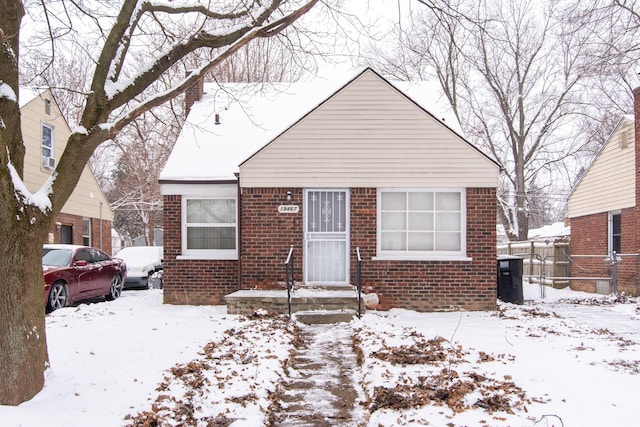 bungalow-style home featuring fence and brick siding