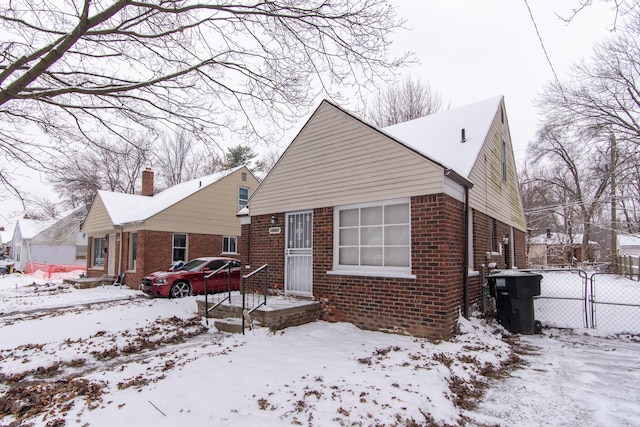 view of front of property featuring brick siding, fence, and a gate