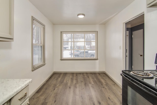 unfurnished dining area featuring light wood-type flooring and baseboards