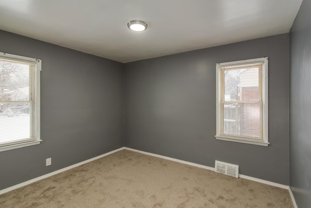 carpeted empty room featuring visible vents and baseboards