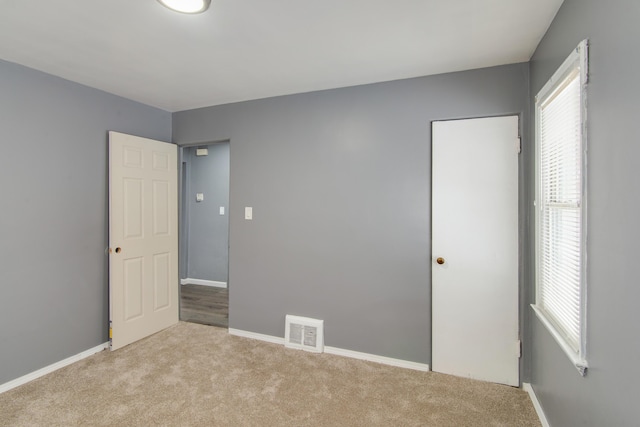 unfurnished bedroom featuring visible vents, baseboards, and carpet