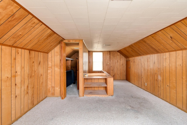 additional living space featuring wood walls, stairway, carpet, and lofted ceiling