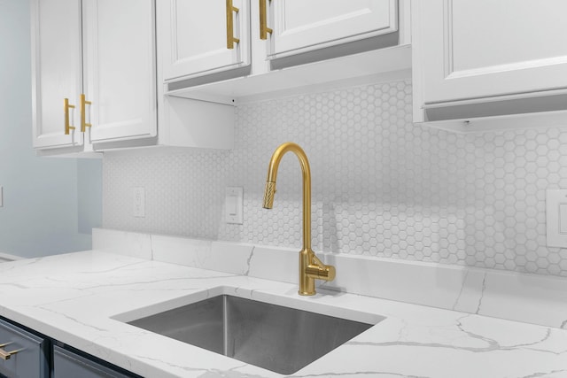 2817 Cumberland Ave, Ann Arbor, MI 48104 - kitchen featuring a sink, white cabinets, light stone counters, and decorative backsplash