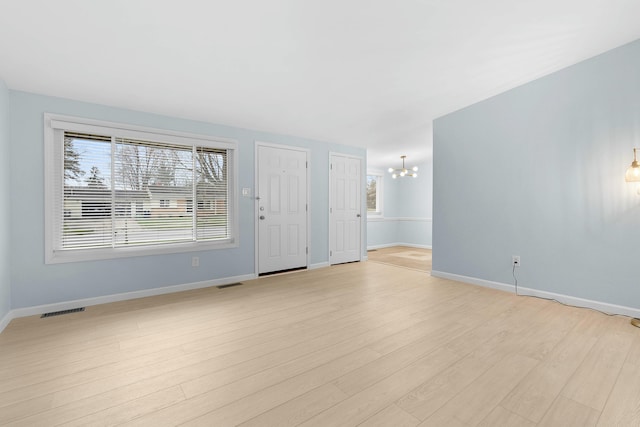 2817 Cumberland Ave, Ann Arbor, MI 48104 - unfurnished living room with light wood-style flooring, baseboards, a notable chandelier, and visible vents