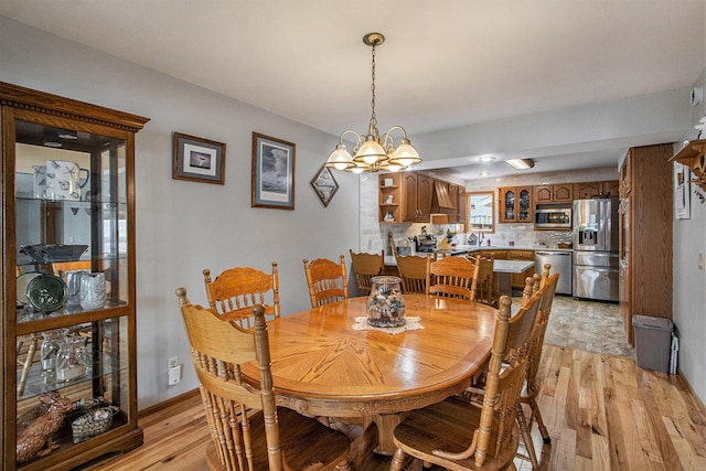 15095 N Barton Lake Dr, Vicksburg, MI 49097 - dining space with light wood-style flooring, a chandelier, and baseboards