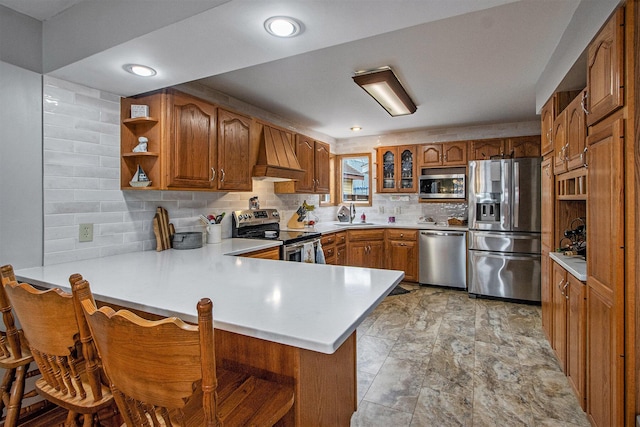 15095 N Barton Lake Dr, Vicksburg, MI 49097 - kitchen with a peninsula, custom exhaust hood, appliances with stainless steel finishes, brown cabinets, and decorative backsplash