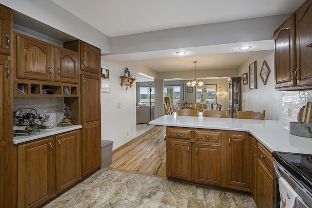 15095 N Barton Lake Dr, Vicksburg, MI 49097 - kitchen with pendant lighting, a peninsula, a chandelier, light countertops, and electric stove