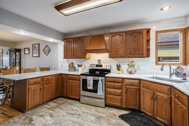 15095 N Barton Lake Dr, Vicksburg, MI 49097 - kitchen with custom exhaust hood, stainless steel electric range, a peninsula, a breakfast bar area, and a sink