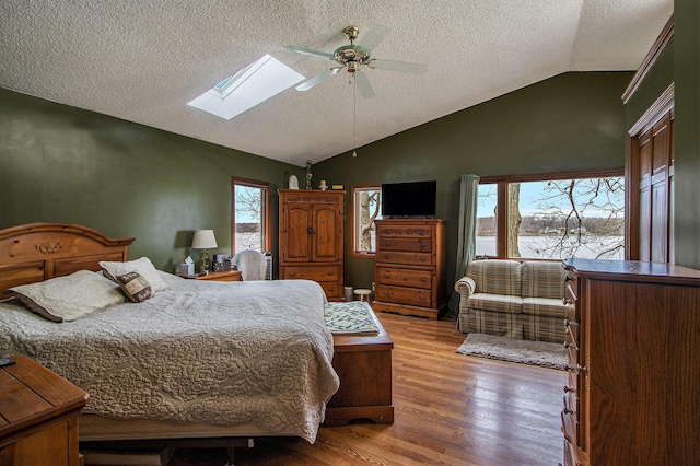 15095 N Barton Lake Dr, Vicksburg, MI 49097 - bedroom featuring a ceiling fan, lofted ceiling with skylight, wood finished floors, and a textured ceiling