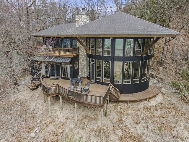 6993 S Lakeshore Dr, Pentwater, MI 49449 - rear view of property featuring a chimney, a shingled roof, stone siding, and a deck