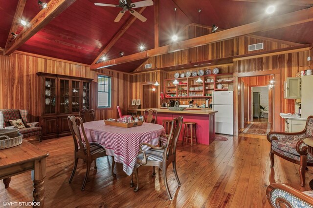 12801 Hills Rd, Buchanan, MI 49107 - dining room featuring beam ceiling, light wood-style floors, wood walls, a ceiling fan, and visible vents