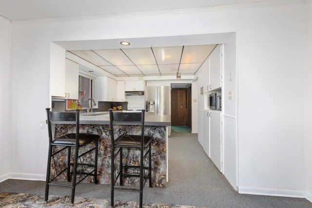 7190 Thornapple River Ct SE, Alto, MI 49302 - kitchen featuring a peninsula, white cabinetry, a sink, and stainless steel fridge