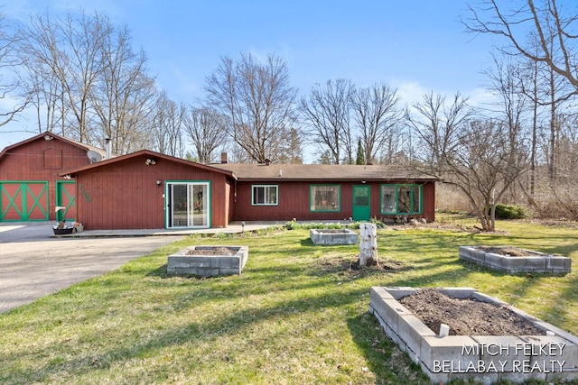 7190 Thornapple River Ct SE, Alto, MI 49302 - view of front of house with a garden, a fire pit, a barn, an outdoor structure, and a front lawn