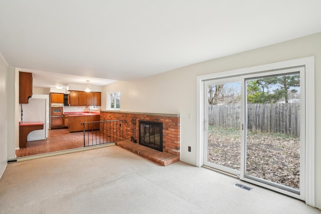2380 Nixon Rd, Ann Arbor, MI 48105 - living area featuring light carpet, a healthy amount of sunlight, a brick fireplace, and visible vents