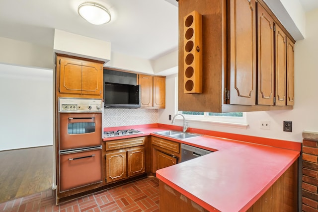 2380 Nixon Rd, Ann Arbor, MI 48105 - kitchen featuring a peninsula, brown cabinets, appliances with stainless steel finishes, brick floor, and a sink