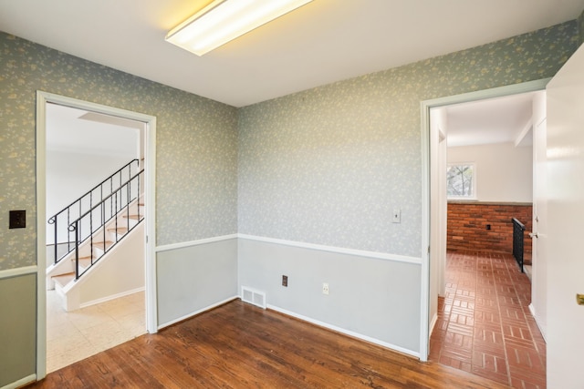 2380 Nixon Rd, Ann Arbor, MI 48105 - unfurnished room with visible vents, a wainscoted wall, stairway, wood finished floors, and wallpapered walls