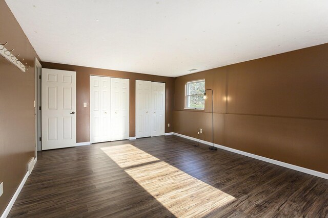 620 Twin Lakes Dr NE, Grand Rapids, MI 49525 - unfurnished bedroom with multiple closets, dark wood finished floors, and baseboards
