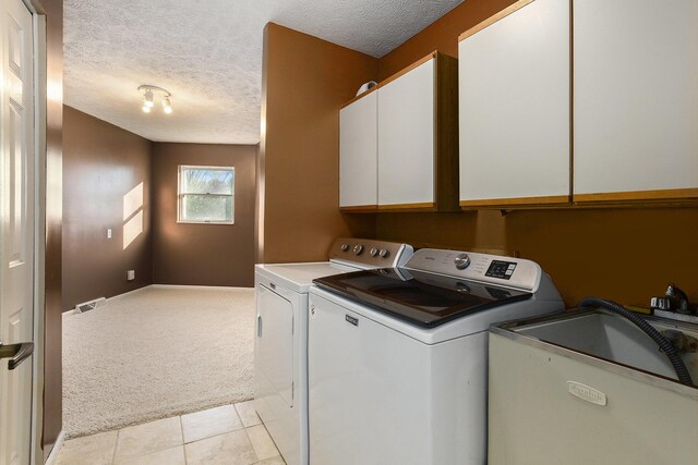 620 Twin Lakes Dr NE, Grand Rapids, MI 49525 - laundry area featuring separate washer and dryer, cabinet space, light colored carpet, a textured ceiling, and light tile patterned flooring