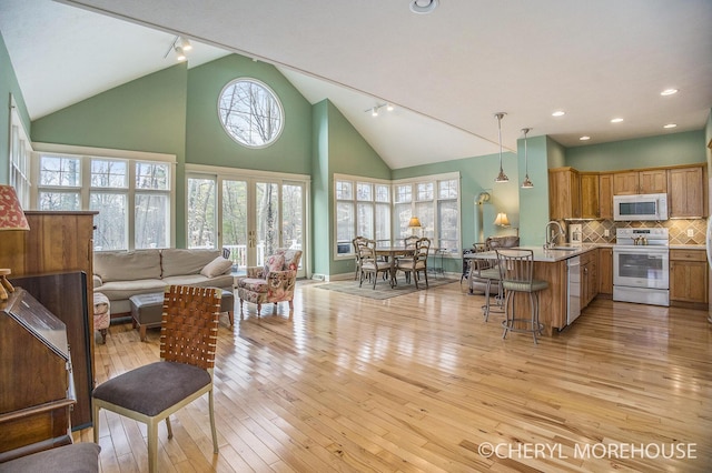 living area with high vaulted ceiling, baseboards, recessed lighting, and light wood-style flooring