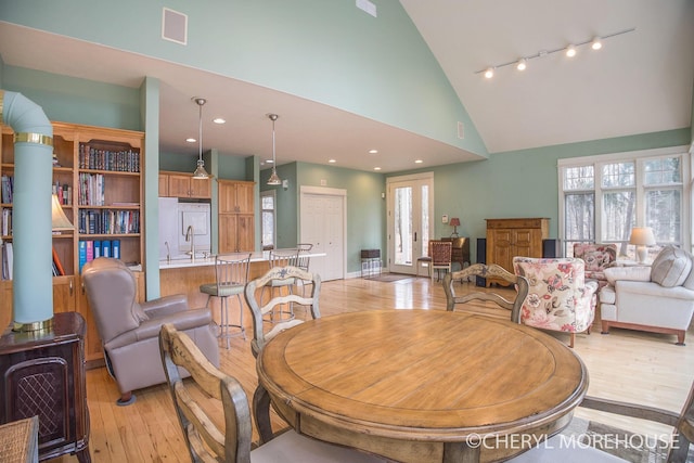 dining space featuring high vaulted ceiling, a healthy amount of sunlight, and light wood-style floors