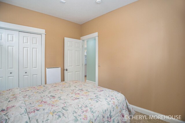 carpeted bedroom featuring a closet and baseboards