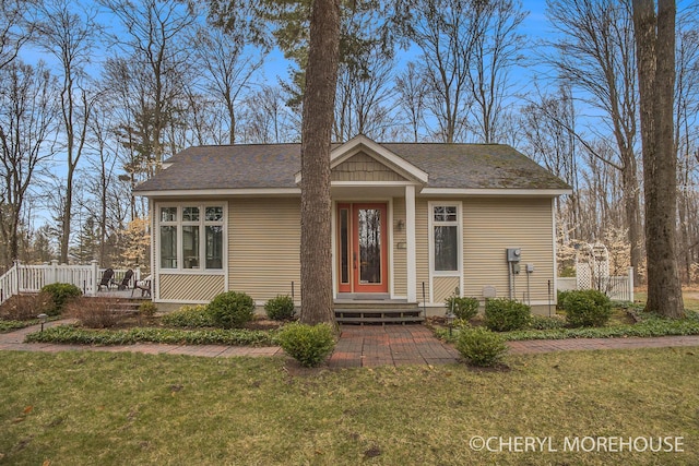 view of front of home featuring roof with shingles and a front lawn