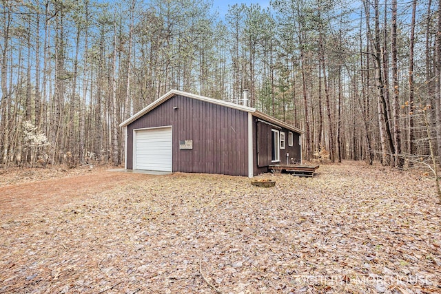 detached garage with a view of trees