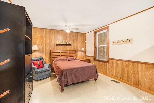 bedroom with wood walls, tile patterned floors, visible vents, wainscoting, and ceiling fan