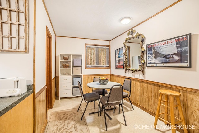 dining area with crown molding, a wainscoted wall, and wooden walls