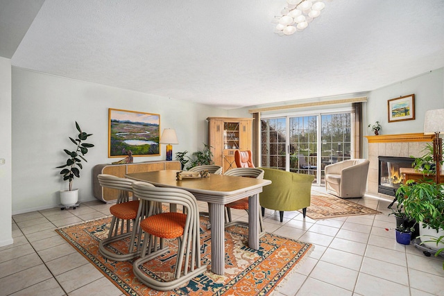 dining room with light tile patterned floors, a tiled fireplace, and a textured ceiling