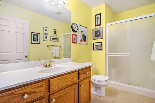 bathroom with tile patterned flooring, a stall shower, toilet, and vanity